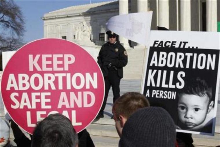 A police officer watches pro-life and pro-choice supporters demonstrating to mark the anniversary of the Supreme Court's 1973 Roe v. Wade abortion decision in Washington, Jan. 24, 2011.