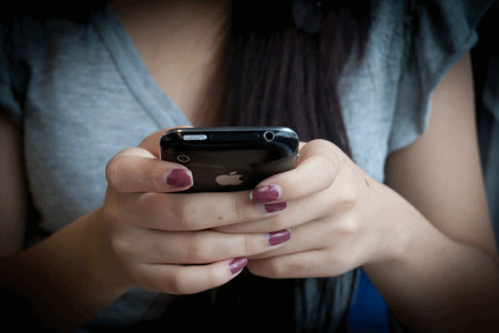 A woman sends text messages on her cell phone. (FILE)