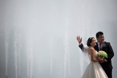 A bride and groom take pictures by the fountains of the Unisphere at Flushing Meadows Corona Park in the borough of Queens in New York July 9, 2013.