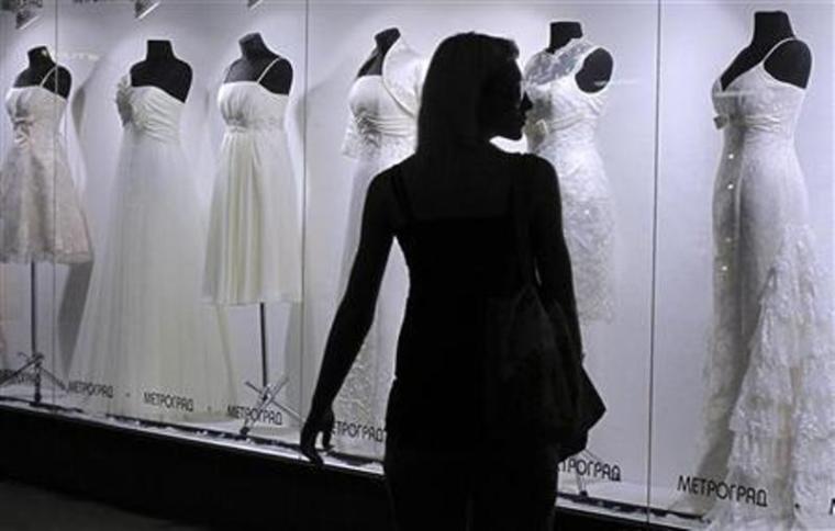 A woman walks by a shop window displaying wedding gowns in Kiev, July 1, 2010.