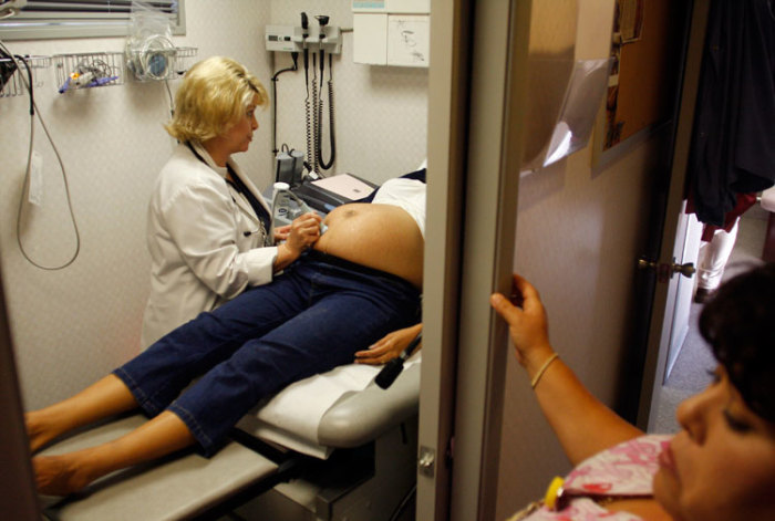 A woman receives an ultrasound by a nurse practitioner during a prenatal exam.