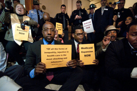 Rev. Raphael Warnock, a pastor at Ebenezer Baptist Church, Rev. Martin Luther King Jr.'s old church, holds a sign that quotes the former civil rights icon: 'Of all forms of inequality, injustice in health care is the most shocking and inhumane,' at a Moral Monday Georgia protest at the Georgia Capitol, March 18, 2014, Atlanta, Ga.