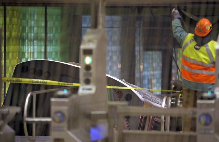 A worker puts up a tarp to cover the scene where a Chicago Transit Authority subway train crashed into a platform at O'Hare International Airport in Chicago March 24, 2014. Thirty-two people were injured after the train derailed and hit a platform early on Monday, with its front car landing on an escalator and stairs, a city fire official said.