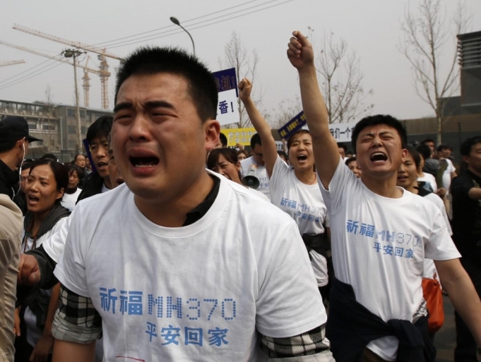 Family members of passengers onboard Malaysia Airlines MH370 cry as they shout slogans during the protest in front of the Malaysian embassy.