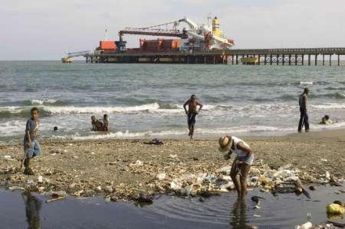 A woman collects rubbish to recycle and make into decorative objects as residents spend a day on the beach next to the main port in Haina February 28, 2009. Researchers will fan out across more than 80 developing countries beginning this month to hunt out and assess many of the world's dirtiest industrial waste sites. The New York-based nonprofit Blacksmith Institute recently led a $200,000 clean up of a battery site in Haina in the Dominican Republic, in which much of the underlying soil was 35 percent lead, a pollutant that leads to severe learning disabilities in children.