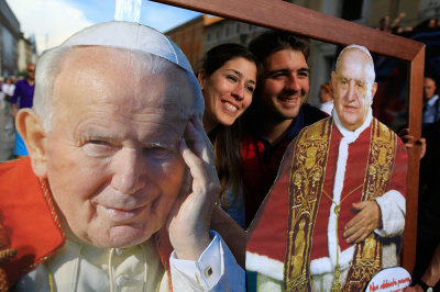 Faithful pose with pictures of Pope John Paul II (L) and Pope John XXIII in front of St. Peter's Square, in Rome, Italy, April 25, 2014.