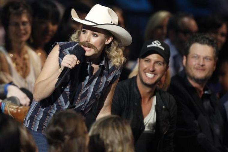 Show host Kristen Bell wears a fake mustache as she speaks during the 2014 CMT Music Awards in Nashville, Tennessee June 4, 2014.