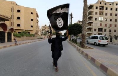 A member loyal to the Islamic State in Iraq and the Levant (ISIL) waves an ISIL flag in Raqqa June 29, 2014.