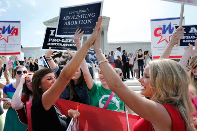 Pro-life demonstrators high five as the ruling for Hobby Lobby was announced outside the U.S. Supreme Court in Washington June 30, 2014. The U.S. Supreme Court on Monday ruled that business owners can object on religious grounds to a provision of U.S. President Barack Obama's healthcare law that requires closely held companies to provide health insurance that covers birth control.