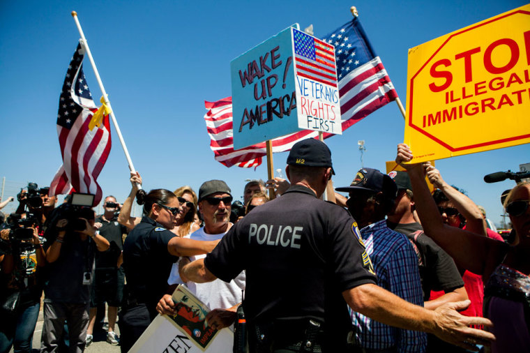 Demonstrators picketing against the arrival of undocumented migrants who were scheduled to be processed at the Murrieta Border Patrol Station block the buses carrying the migrants in Murrieta, California July 1, 2014. Some 140 undocumented immigrants, many of them women with children, will be flown from Texas to California and processed through a San Diego-area U.S. Border Patrol station as federal officials deal with a crush of Central American migrants at the border, a local mayor said on Monday.