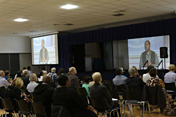 Worshippers watch pastor Creflo Dollar preach remotely during a Sunday, June 22, 2014, service in the Gold Coast in Queensland, Australia.