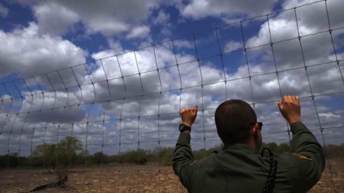 An immigration agent looks out at the desert near Falfurrias, Texas, March 29, 2013.