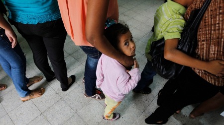 Women and their children wait in line to register at the Honduran Center for Returned Migrants after being deported from Mexico. To stem the flow north, a new US-funded Honduran Special Tactical Operations Group is working to spot unaccompanied minors crossing the Honduran border.