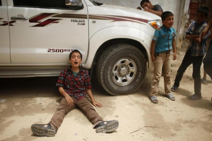 The son (L) of one of the Palestinian members of Tayseer Al-Batsh's family, who hospital officials said were killed in an Israeli airstrike on Saturday, mourns during their funeral in Gaza City July 13, 2014. The Israeli airstrike on the family home of Al-Batsh, Gaza's police chief, killed 18 people, Gaza's health ministry said.