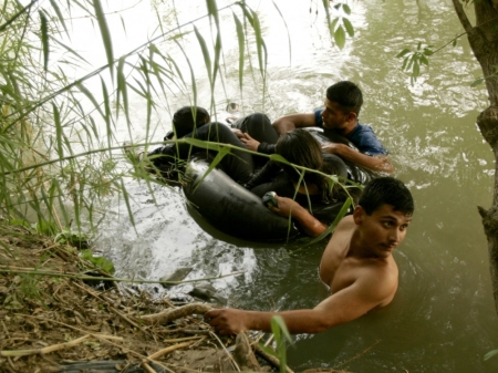 A group of illegal aliens wait on the U.S. side of the Rio Grande river, after floating across in a tire tube, in Laredo, Texas May 2, 2006. U.S. Border Patrol agents intercepted the group and they eventually went back to Mexico.