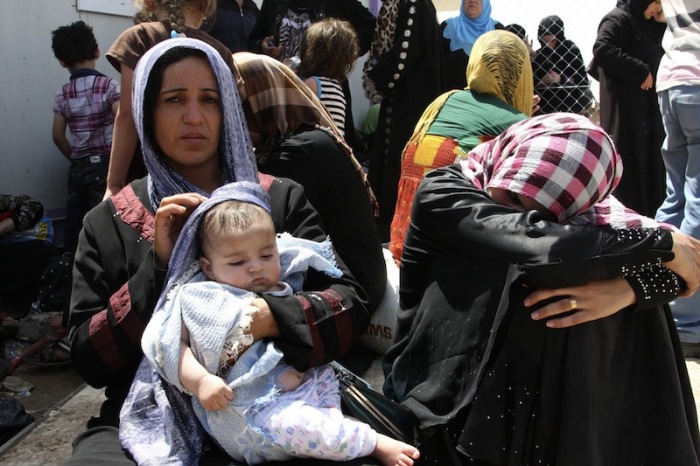 Families fleeing the violence in the Iraqi city of Mosul wait at a checkpoint in outskirts of Arbil, in Iraq's Kurdistan region in June 2014.