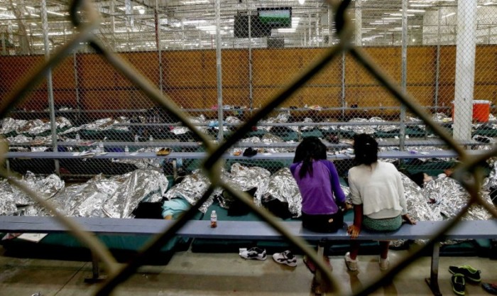 Two young girls watch a World Cup soccer match on a television from their holding area where hundreds of mostly Central American immigrant children are being processed and held at the U.S. Customs and Border Protection Nogales Placement Center in Nogales, Arizona, June 18, 2014.