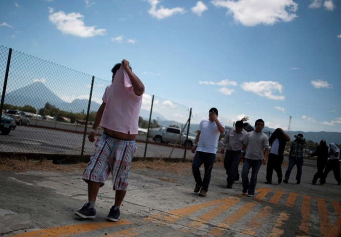 Illegal migrants from Guatemala, deported from Phoenix, Arizona, in the U.S., cover their faces as they arrive at an air force base in Guatemala City July 22, 2014. The flight transporting the illegal Guatemalan migrants arrived on Tuesday after they were sent back from the U.S., according to immigration authorities. A growing wave of families and unaccompanied minors fleeing Guatemala, El Salvador and Honduras are streaming by the thousands into the United States by way of human trafficking networks through Mexico.