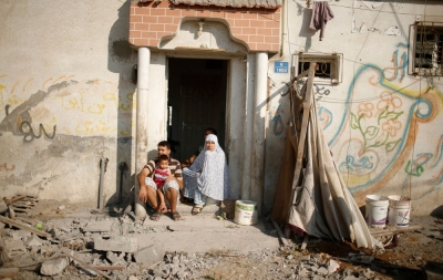 Palestinians sit outside their damaged house as they look at a neighbouring house, which witnesses said was destroyed in an Israeli air strike, in Gaza City August 9, 2014. 