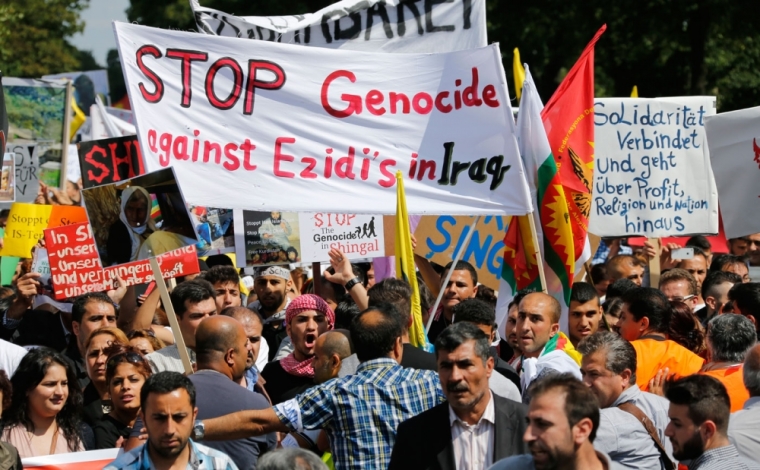 Kurds of the ethnic minority of Yazidis hold up a banner reading 'Stop genocide against Yazidis in Iraq' as they march through the streets of Bielefeld August 9, 2014. Some 10,000 ethnic Kurds of the Yazidis sect, who practice an ancient faith related to Zoroastrianism, protested in the western German city on Saturday against Islamic State (IS) militants, who are surging across northern Iraq near the Kurdistan borders in their drive to eradicate unbelievers such as Christians and Yazidis.