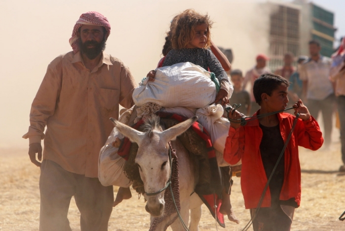 Displaced people from the minority Yazidi sect, fleeing violence from forces loyal to the Islamic State in Sinjar town, walk towards the Syrian border as others ride on a donkey on the outskirts of Sinjar mountain, near the Syrian border town of Elierbeh of Al-Hasakah Governorate August 11, 2014. Islamic State militants have killed at least 500 members of Iraq's Yazidi ethnic minority during their offensive in the north, Iraq's human rights minister told Reuters on Sunday. The Islamic State, which has declared a caliphate in parts of Iraq and Syria, has prompted tens of thousands of Yazidis and Christians to flee for their lives during their push to within a 30-minute drive of the Kurdish regional capital Arbil. Picture taken August 11, 2014.