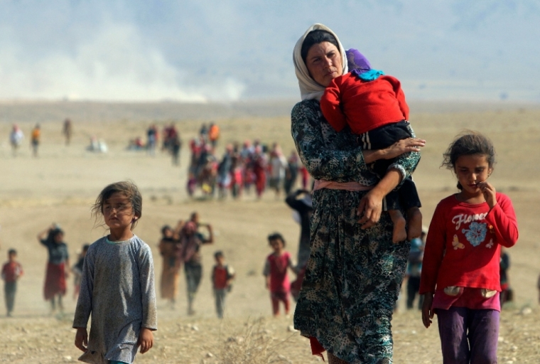 Displaced people from the minority Yazidi sect, fleeing violence from forces loyal to the Islamic State in Sinjar town, walk toward the Syrian border, on the outskirts of Sinjar mountain, near the Syrian border town of Elierbeh of Al-Hasakah Governorate, August 11, 2014. The Islamic State, which has declared a caliphate in parts of Iraq and Syria, has prompted tens of thousands of Yazidis and Christians to flee for their lives during their push to within a 30-minute drive of the Kurdish regional capital Arbil.