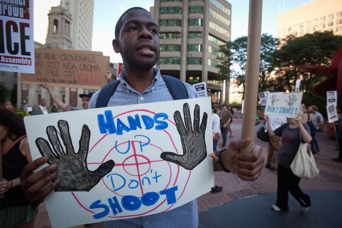 A protester carries a sign as he participates in a protest against the police in Ferguson, Missouri, in the Manhattan borough of New York August 18, 2014. A few dozen protesters gathered at New York City Police headquarters to show their support for Michael Brown, who was killed by police in Ferguson on August 9, 2014.