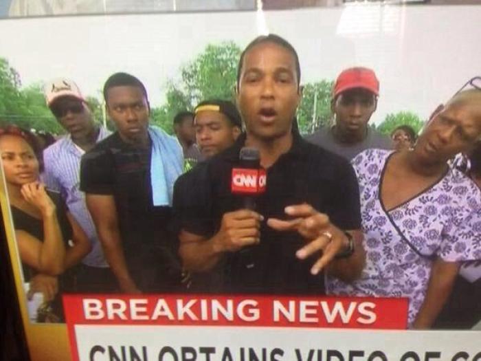 Protestors look at CNN Anchor Don Lemon strangely as he reports live