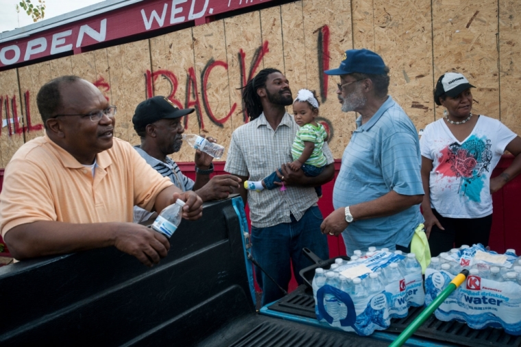 Bishop Edwin Bass (L), president of the Church of God in Christ Urban Initiatives and other volunteers gather as they finish cleanup efforts after an other night of demonstrations on the streets of Ferguson, Missouri, August 19, 2014. Police said they came under heavy gunfire and arrested 31 people during another night of racially charged protests in Ferguson, sparked by the fatal shooting of unarmed black teenager Michael Brown, by a white policeman 10 days ago.