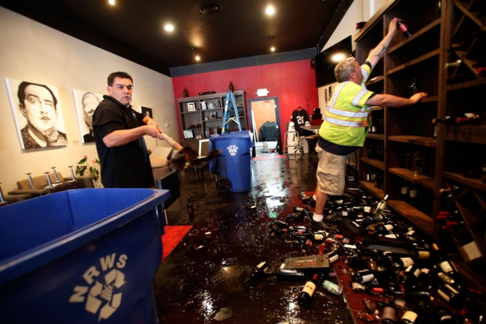 Rick Ruiz (L) and Tyler Paradise gather broken wine bottles from the floor of their Cult Following Wine Bar after an earthquake in Napa, California August 24, 2014. The 6.0 earthquake rocked wine county north of San Francisco early Sunday, injuring dozens of people, damaging historical buildings, setting some homes on fire and causing power outages around the picturesque town of Napa.