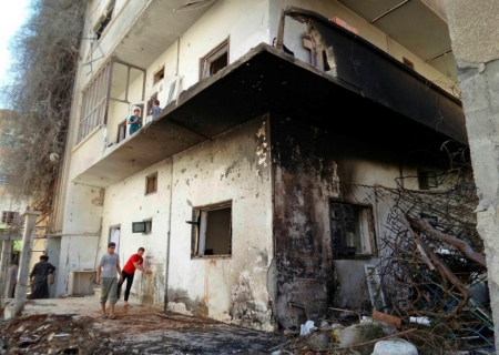 Men walk past a damaged building in Raqqa, an Islamic State power base in Syria, Sept. 8, 2014. Syrian government warplanes killed at least 60 civilians including a dozen children in two days of air strikes on Islamic State-held territories at the weekend, including the Islamic State stronghold of Raqqa, activists said on Monday. President Bashar al-Assad's military has stepped up an aerial campaign over the last three months against Islamic State, an al Qaeda offshoot that controls about a third of Syria's territory, much of it desert in the north and east.