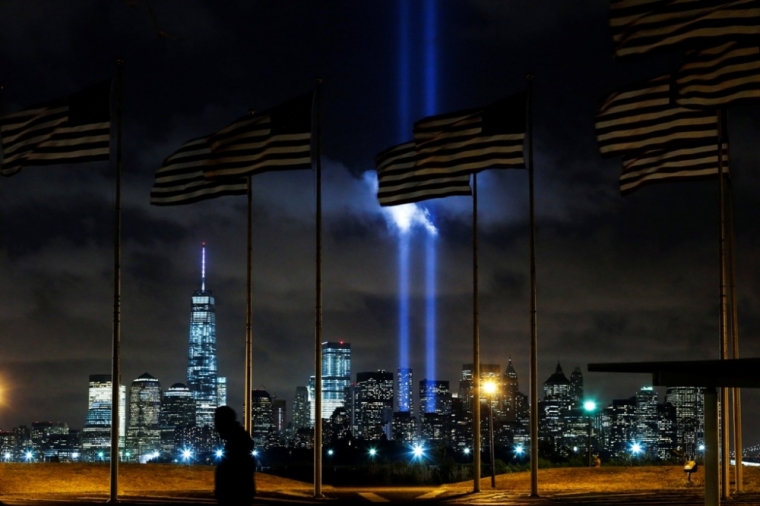 A man walks past as the Tribute in Light is illuminated on the skyline of lower Manhattan during events marking the 13th anniversary of the 9/11 attacks on the World Trade Center in New York, Sept. 10, 2014. Until a few months ago, the part of New York City where crowds gathered Thursday morning to mark the 13th anniversary of the Sept. 11, 2001, attacks on the U.S. had been mostly fenced off to the public. This year, for perhaps the first time since the attacks, a sense of normalcy and openness has taken root in the city blocks where two airliners hijacked by militants from al Qaeda crashed into the World Trade Center's twin towers.