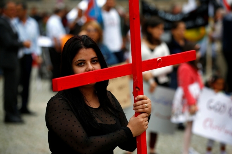 A woman holds a cross during a rally organized by Iraqi Christians in Germany denouncing persecution by the Islamic State terror group against Christians living in Iraq, in Berlin, Aug. 17, 2014.