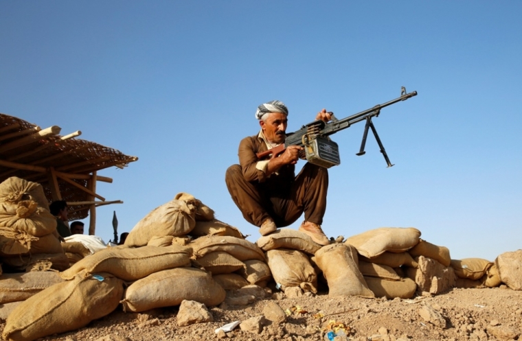 A Kurdish Peshmerga fighter takes position he keep watch on two moving vehicles belonging to the Islamic State at the Bakirta front line, near the town of Makhmur south of Erbil, Iraq, September 10, 2014.