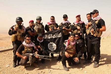 Kurdish Peshmerga fighters pose with an Islamic State flag, which they pulled down after capturing Mount Batnaya, near Zummar September 20, 2014.