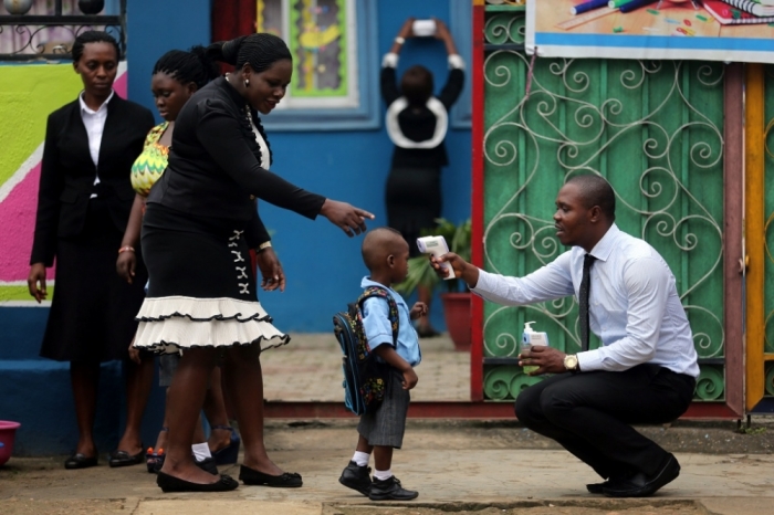 A school official takes a pupil's temperature using an infrared digital laser thermometer in front of the school premises, at the resumption of private schools, in Lagos, September 22, 2014. Nigeria and Senegal, two of the five countries affected by the world's worst ever Ebola outbreak are managing to halt the spread of the disease, the World Health Organization said on Monday, although the overall death toll rose to 2,793 out of 5,762 cases.