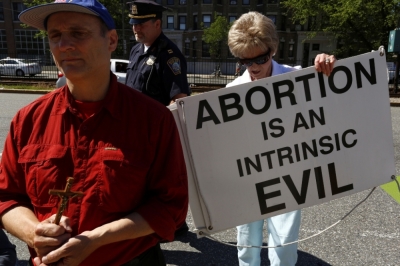 An abortion protester moves her sign out of the street in front of a Planned Parenthood clinic in Boston, Massachusetts, June 28, 2014.