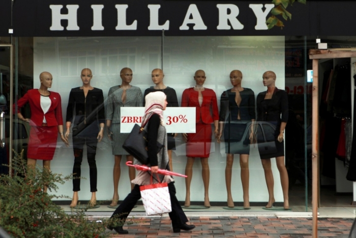 A woman wearing a hijab walks past a shop selling women's clothing in Pristina, Kosovo, September 26, 2014.