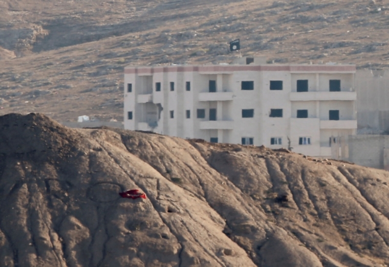 A black flag belonging to the Islamic State is seen near the Syrian town of Kobani, as pictured from the Turkish-Syrian border near the southeastern town of Suruc in Sanliurfa province, October 6, 2014. Islamic State militants raised their flag on a building on the eastern outskirts of the Syrian border town of Kobani on Monday after an assault of almost three weeks, but the town's Kurdish defenders said they had not reached the city center.