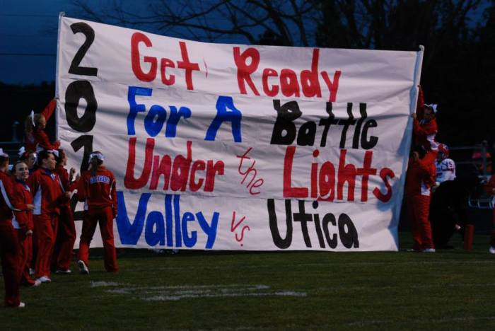 Cheerleaders at the Licking Valley High School in Newark, Oh. hold up the team banner before the school's football team storms through it.