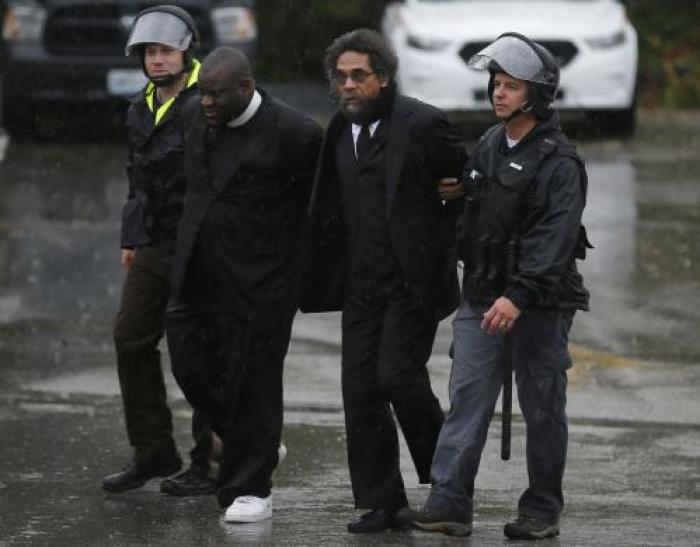 Activist Cornel West (2nd R) is detained by police during a protest at the Ferguson Police Department in Ferguson, Missouri, October 13, 2014.