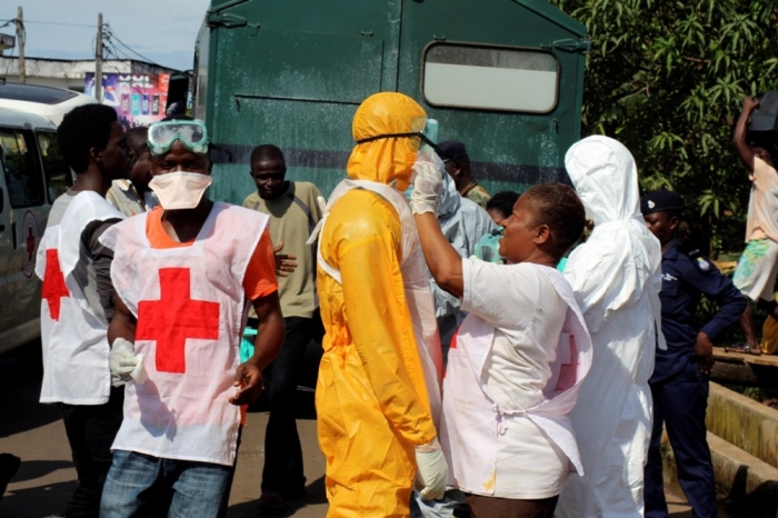 A health worker fixes another health worker's protective suit in the Aberdeen district of Freetown, Sierra Leone, October 14, 2014.