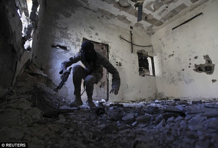 A guerrilla fighter crouches down inside of a war-torn house in the Syrian province of Deir al-Zor. More guerrilla groups are starting to attack Islamic State fighters in retaliation for the group's brutality.