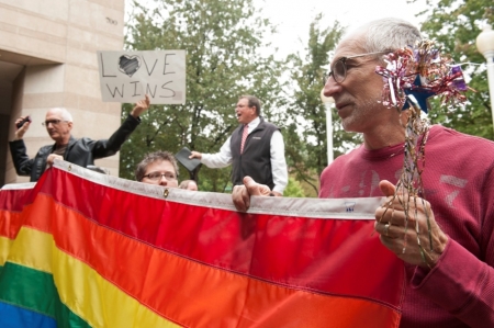 Larry Ferri (R) and Brandi Morris (C) hold large rainbow flag as gay couples marry outside of Mecklenburg County Register of Deeds office in Charlotte, North Carolina, October 13, 2014. Monday was the first day that Mecklenburg County issued marriage licenses to gay couples. Two protesters were at the gathering, but pro-gay rights activists blocked the protesters from interfering with ceremonies.