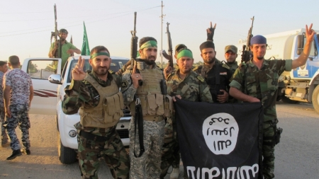 Shi'ite fighters pose with a black flag belonging to the Islamic State, which they pulled down after capturing the town of Jurf al-Sakhar from the Islamic State militants, south of Baghdad, Iraq, October 26, 2014.