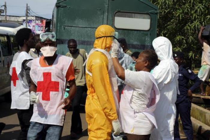 A health worker fixes another health worker's protective suit in the Aberdeen district of Freetown, Sierra Leone, October 14, 2014.