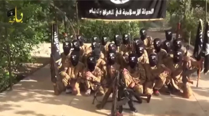 Islamic State child soldiers posing for a group picture underneath the Islamic State's black flag.