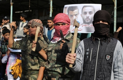 Masked Palestinians hold axes and a gun as they celebrate with others an attack on a Jerusalem synagogue, in Rafah in the southern Gaza Strip, November 18, 2014. Two Palestinians armed with a meat cleaver and a gun killed four people in a Jerusalem synagogue on Tuesday before being shot dead by police, the deadliest such incident in six years in the holy city amid a surge in religious conflict.