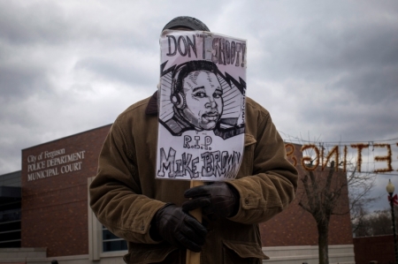 A man, who was demanding the criminal indictment of a white police officer who shot dead an unarmed black teenager in August, holds an image of Michael Brown outside the Ferguson Police Station in Missouri, November 24, 2014. A St. Louis Country prosecutor is expected to make an announcement later on Monday on the grand jury that has been reviewing whether to charge a Ferguson, Missouri, police officer in the August shooting of an unarmed black teen, CNN reported, citing an unnamed law enforcement source. The grand jury has been meeting for more than three months, considering the Aug. 9 incident in which white police officer Darren Wilson shot and killed 18-year-old Michael Brown.