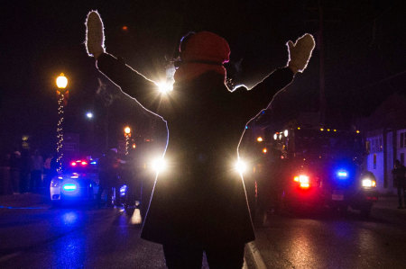 A female protester raises her hands while blocking police cars in Ferguson, Missouri, November 25, 2014. More than 2,000 National Guard troops spread out across the St. Louis area on Tuesday to prevent another night of rioting and looting after a grand jury declined to indict Darren Wilson, a white police officer, in the August shooting of unarmed black teenager Michael Brown.